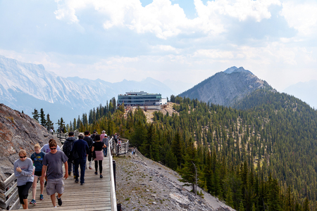 BANFF, CANADA - AUG 1, 2018: Visitors walk the wooden boardwalk on top of Sulphur Mountain between the Gondola summit and Sanson's Peak for a panoramic view of the mountain range in the Canadian Rockies of Banff National Park.のeditorial素材