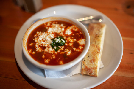 Bowl of Tomato soup with goat cheese and flat bread stick.の写真素材