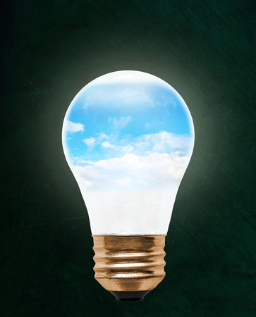 Blue sky inside floating light bulb with copy space. Concept of ecology, environmental conservation; green alternative.の写真素材
