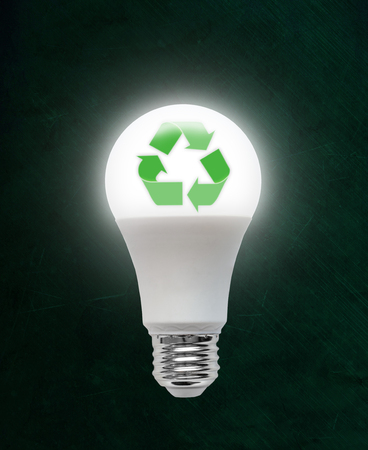 Illuminated energy efficient Light Emitting Diode LED light bulb with recycling symbol inside. Concept of ecology, environmental conservation; green alternative.の写真素材