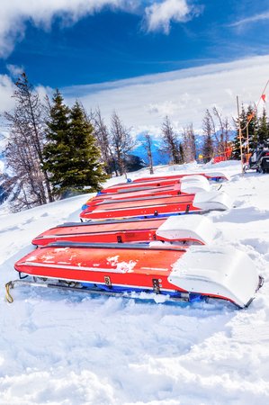 Rows of ski patrol toboggans or rescue sleds lie on snow on mountain ski resort. Also known as akia or emergency rescue sledg, it is used by mountain rescue teams in winter to evacuate an injured skier or snowboarder.の写真素材