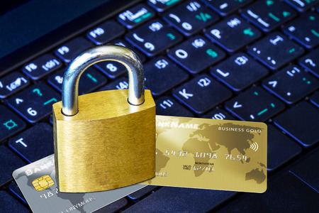 Golden padlock on top of fictitious credit cards on computer keyboard. Concept of Internet security, data privacy, cybercrime prevention for online shopping transaction payments.の写真素材