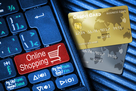 Close up of computer laptop keyboard on generic credit cards with red button Online Shopping concept. Idea of Internet shopping and data privacy, security, cyber crime prevention.の写真素材