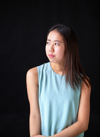 Beautiful young Asian female teen model posing in studio on black background.の写真素材