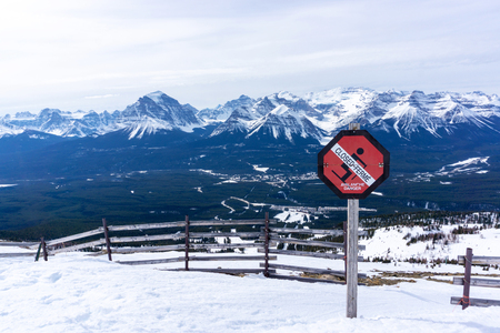 An avalanche danger warning sign prevents skiers from venturing into dangerous territory with the picturesque Canadian Rockies of Alberta in the background.の写真素材