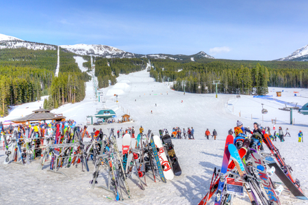LAKE LOUISE, CANADA - MAR 23, 2019: Skis and snowboards on racks at Lake Louise in the Canadian Rockies near Banff with ski slopes and chair lifts in the background.のeditorial素材