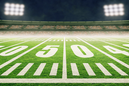 Close up of American football stadium field with yard line markings and spotlight with blurred background.の写真素材