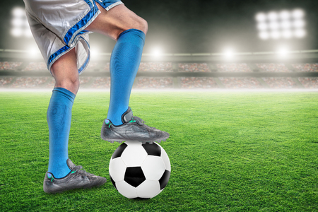 Soccer player in action with football in brightly lit outdoor stadium. Focus on foreground and soccer ball with shallow depth of field on background and copy space.の写真素材