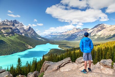 A young hiker looks at Peyto Lake from Bow Summit in Banff National Park on the Icefields Parkway. The glacier-fed lake is famous for its bright turquoise colored waters in the summer.の写真素材