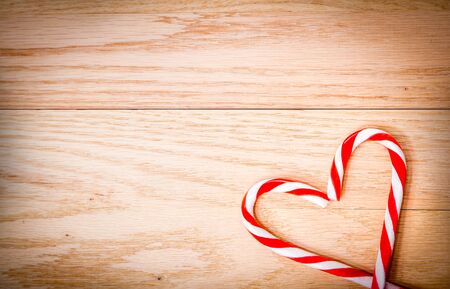Christmas background with candy cane arranged in a heart shape on wooden table with copy spaceの写真素材