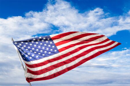Stars and Stripes USA Flag waving against a blue sky background. Concept of patriotism, Veterans Day or war memorial events.の写真素材