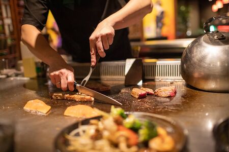 Teppanyaki chef cooking Japanese Wagyu beef and filet mignon steak on hot metal plateの写真素材