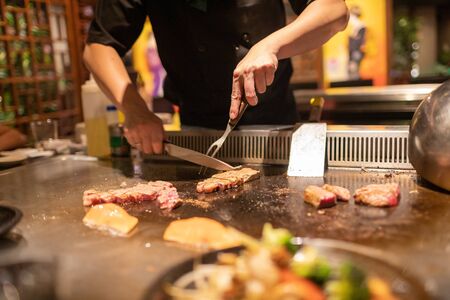 Teppanyaki chef cooking Japanese Wagyu beef and filet mignon steak on hot metal plateの写真素材