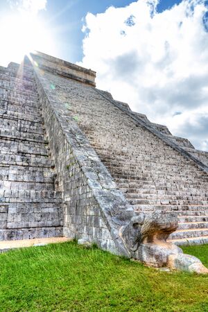 Sun peering over the Pyramid of Kukulcan or El Castillo at Chichen Itza, Mexico. For centuries, at sunset on equinox day, a snake-like shadow descends on the temple stairs to the head of the feathered serpent at the base of the steps.  it is one of the New Seven Wonders of the World.の写真素材