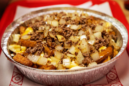 Famous Canadian cuisine known as poutine with hand cut French fries and cheese curds topped with...