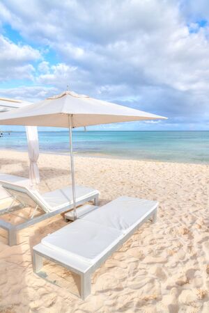 Lounge chair beds and umbrella at white sandy beach in the Caribbean coast of Riviera Maya in Cancun, Mexico.の写真素材