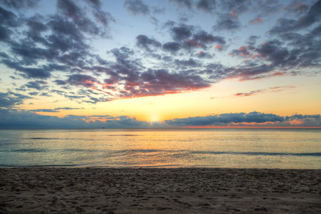 Beautiful sunrise by the beach at Cancun, Mexico, with golden reflections on Caribbean Sea.