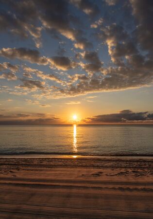 Beautiful sunrise by the beach at Cancun, Mexico, with golden reflections on Caribbean Sea.の写真素材