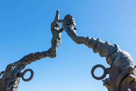 PLAYA DEL CARMEN, MEXICO - DEC. 26, 2019: Close up of Portal Maya, a bronze sculpture of a man and woman clasping hands as their bodies form a 52.5 foot high arch at Fundadores Park on the Caribbean beach in Riviera Maya, Mexico. The public artwork by Artのeditorial素材
