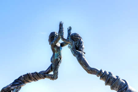 PLAYA DEL CARMEN, MEXICO - DEC. 26, 2019: Close up of Portal Maya, a bronze sculpture of a man and woman clasping hands as their bodies form a 52.5 foot high arch at Fundadores Park on the Caribbean beach in Riviera Maya, Mexico. The public artwork by Artのeditorial素材