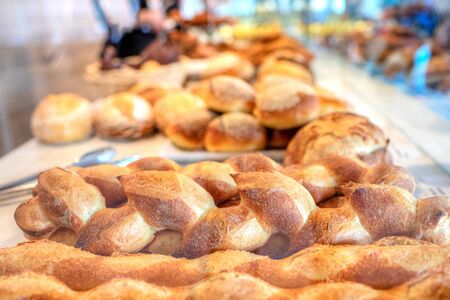 Trays of freshly baked artisan bread loaves at the food market. Focus on the bread in the foreground, with defocused background.の写真素材