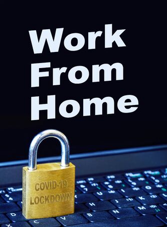 COVID-19 coronavirus lockdown concept with golden padlock on computer laptop keyboard with work from home text on monitor. Idea of self-isolation, quarantine and social distancing to control spread of virus pandemic.の写真素材