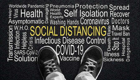 Person standing over Social Distancing word cloud. Concept of social distancing measure to control worldwide COVID-19 coronavirus pandemic. Black and white effect with Social Distancing word in deliberate yellow.の写真素材