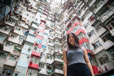 Chinese girl exploring the urban landscape of Hong Kong's crammed public housing quarters in Quarry Bay on Hong Kong Island, one of the most densely populated cities in the world.の写真素材