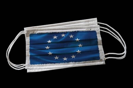Multiple surgical face masks with EU flag printed. Isolated on black background. Concept of face mask usage in the European Union effort to combat Covid-19 coronavirus pandemic.の写真素材