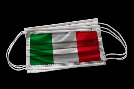 Multiple surgical face masks with Italy flag printed. Isolated on black background. Concept of face mask usage in the Italian effort to combat Covid-19 coronavirus pandemic.の写真素材