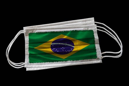 Surgical face masks with Brazil flag printed. Isolated on black background. Concept of face mask usage in Brazilian effort to combat Covid-19 coronavirus pandemic.の写真素材