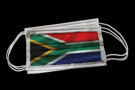 Surgical face masks with South Africa flag printed. Isolated on black background. Concept of face mask usage in South African effort to combat Covid-19 coronavirus pandemic.の写真素材