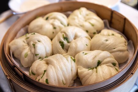 Chinese dim sum steamed scallion spring onion bun rolls served in a bamboo steamer. Dim sum is a unique culinary art form that originated with the Cantonese in southern China and Hong Kong.の写真素材