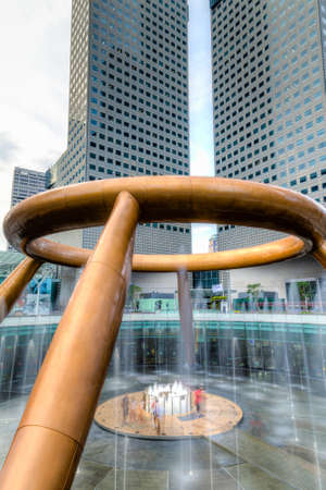 SINGAPORE - MARCH 26, 2015 : Tourists walk toward the Fountain of Wealth believed to impart luck to anyone encircling it 3 times and touching the water in the middle. The largest fountain in the world is located in the commercial complex of Suntec City, Sのeditorial素材