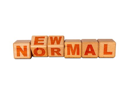 NEW NORMAL word on engraved wooden alphabet cube blocks. Concept of new normal lifestyle after COVID-19 coronavirus pandemic with social distancing, hand washing, wearing face mask in social settings.の写真素材