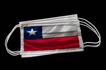 Surgical face masks with flag of Chile printed. Isolated on black background. Concept of face mask usage in the Chilean effort to combat Covid-19 coronavirus pandemic.の写真素材