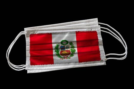 Surgical face masks with flag of Peru printed. Isolated on black background. Concept of face mask usage in the Peruvian effort to combat Covid-19 coronavirus pandemic.の写真素材