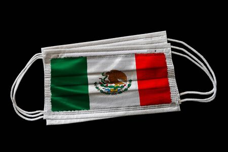 Surgical face masks with flag of Mexico printed. Isolated on black background. Concept of face mask usage in the Mexican effort to combat Covid-19 coronavirus pandemic.の写真素材