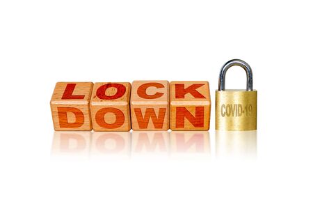 Lockdown due to Covid-19 coronavirus outbreak pandemic. Concept of self isolation or quarantine message engraved on wooden blocks on white background.の写真素材