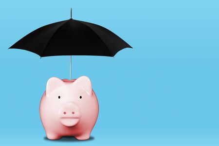 Saving for a rainy day with pink piggy bank and umbrella. Concept of financial security, savings, insurance coverage, wealth management, etc.の写真素材