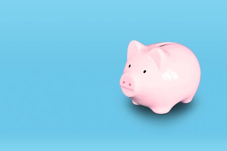 Pink piggy bank isolated on right of blue background with copy space.の写真素材