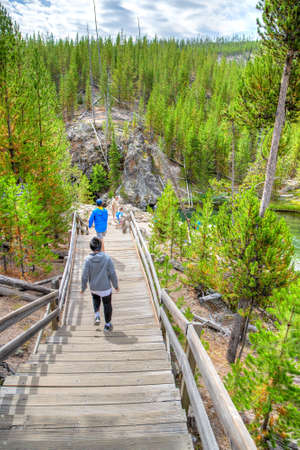 Wyoming, USA - Aug. 24, 2019: Visitors walking down wooden stairs toward Firehole River in Yellowstone National Park, Wyoming, USA. The river flows through several significant geyser basins in Yellowstone National Park.のeditorial素材