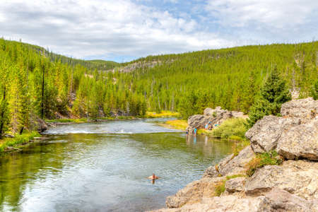 Wyoming, USA - Aug. 24, 2019: Visitors swimming and cooling off at Firehole River in Yellowstone National Park, Wyoming, USA. The river flows through several significant geyser basins in Yellowstone National Park.のeditorial素材