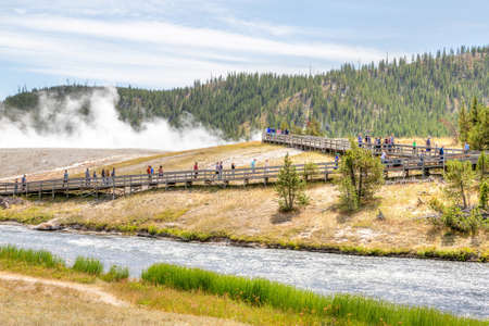 Wyoming, USA - Aug. 24, 2019: Visitors approach the footbridge to Grand Prismatic Spring in Yellowstone National Park with steam rising from the thermal landscape of Excelsior Geyser in the background.のeditorial素材