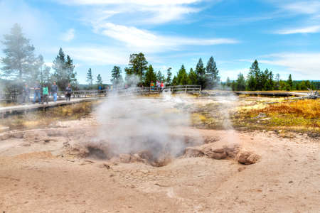 Wyoming, USA - Aug. 24, 2019: Tourists visiting a fumarole at Fountain Paint Pot Trail in the Lower Geyser Basin of Yellowstone National Park. The hiss and roar comes from gases rushing through the vent in the form of hot steam.のeditorial素材