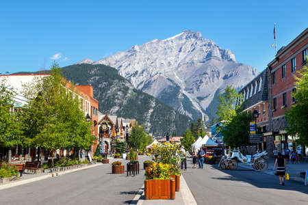 BANFF, CANADA - JULY 29, 2020: Tourists walk along Banff Avenue in Banff National Park with Cascade Mountain in the background. The street was closed due to COVID-19 to allow for more social distancing among visitors.のeditorial素材