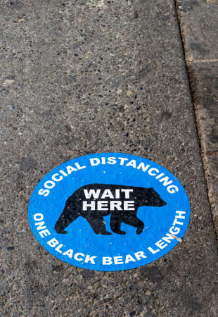 BANFF, CANADA - JULY 29, 2020: Social Distancing road pavement sticker to help visitors at popular Banff National Park to keep a safe distance when shopping and dining during COVID-19 Coronavirus pandemic.のeditorial素材