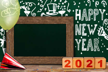 Happy New Year 2021 celebration with background chalkboard party theme and wooden frame copy space surrounded by balloon, party hat, confetti and wooden blocks.の写真素材