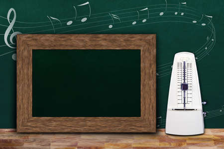 Music class concept with musical notes on background chalkboard and wooden frame copy space next to white mechanical metronome.の写真素材