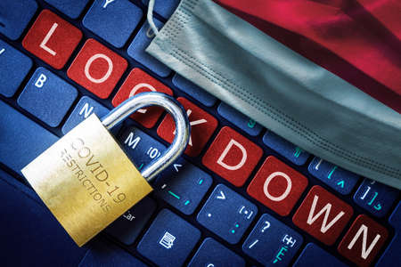 Indonesia COVID-19 coronavirus lockdown restrictions concept illustrated by padlock on laptop red alert keyboard buttons and face mask with Indonesian flag.の写真素材